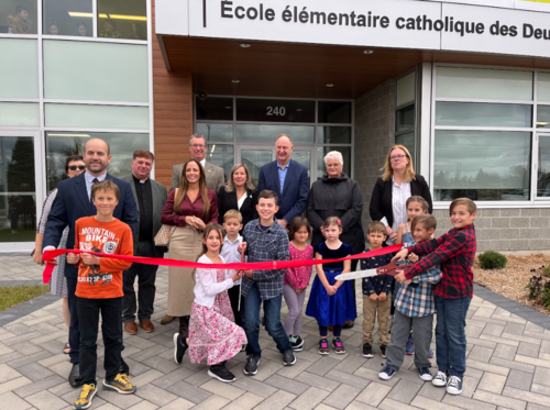 ruban rouge coupé devant l'école lors de l'inauguration, par des élèves et membres du personnel