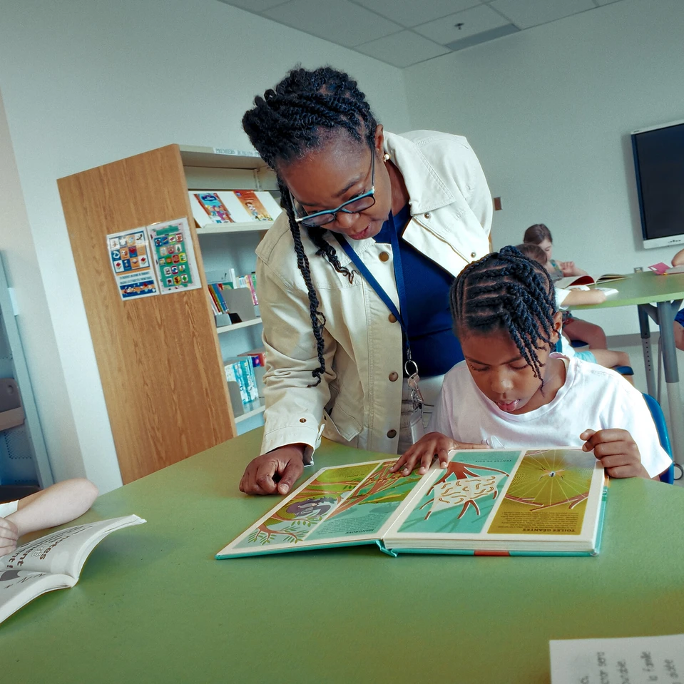 enseignante appui une jeune élève dans sa lecture